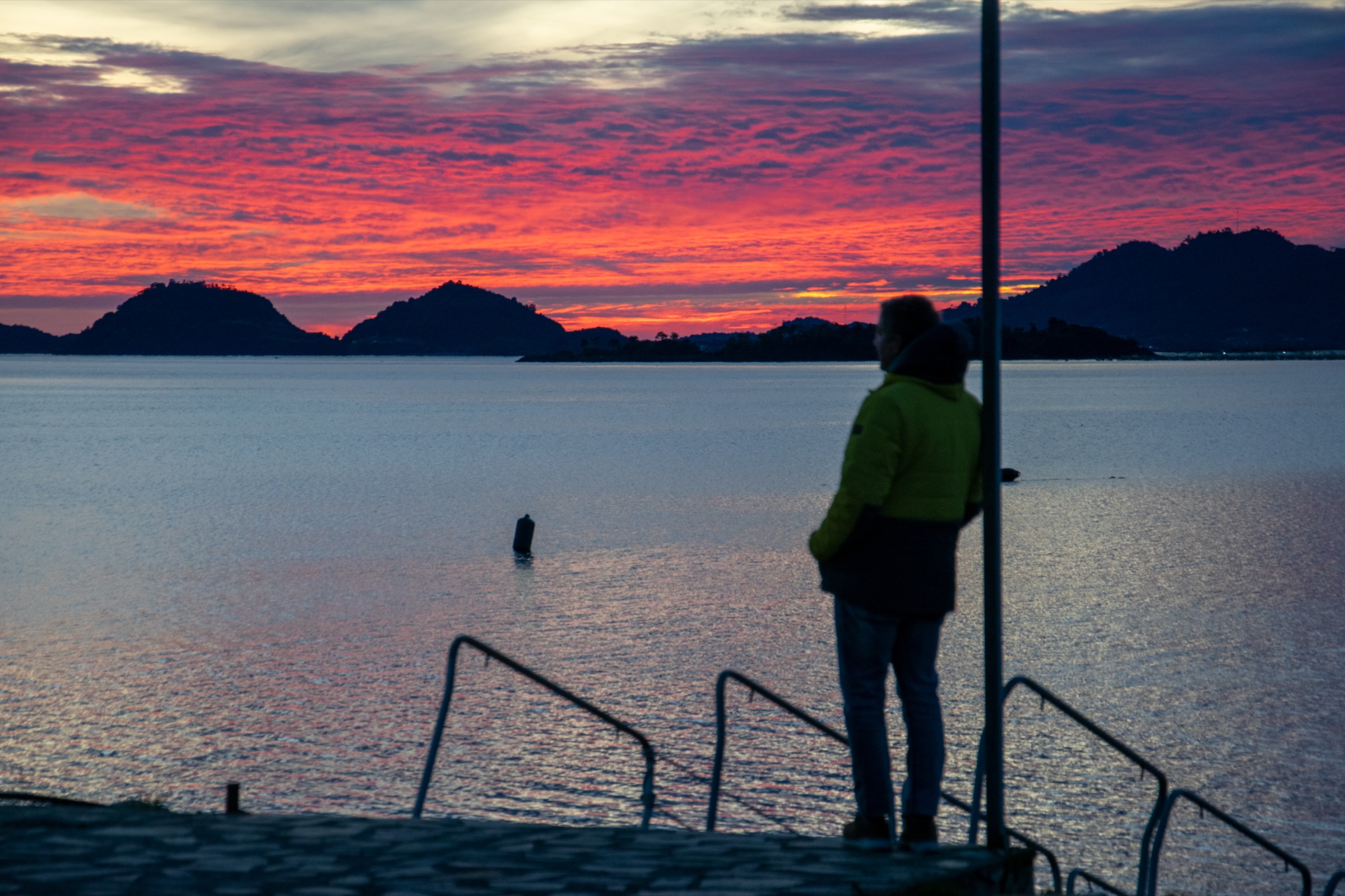 Pasajero contemplando el atardecer desde el muelle del Skorpios