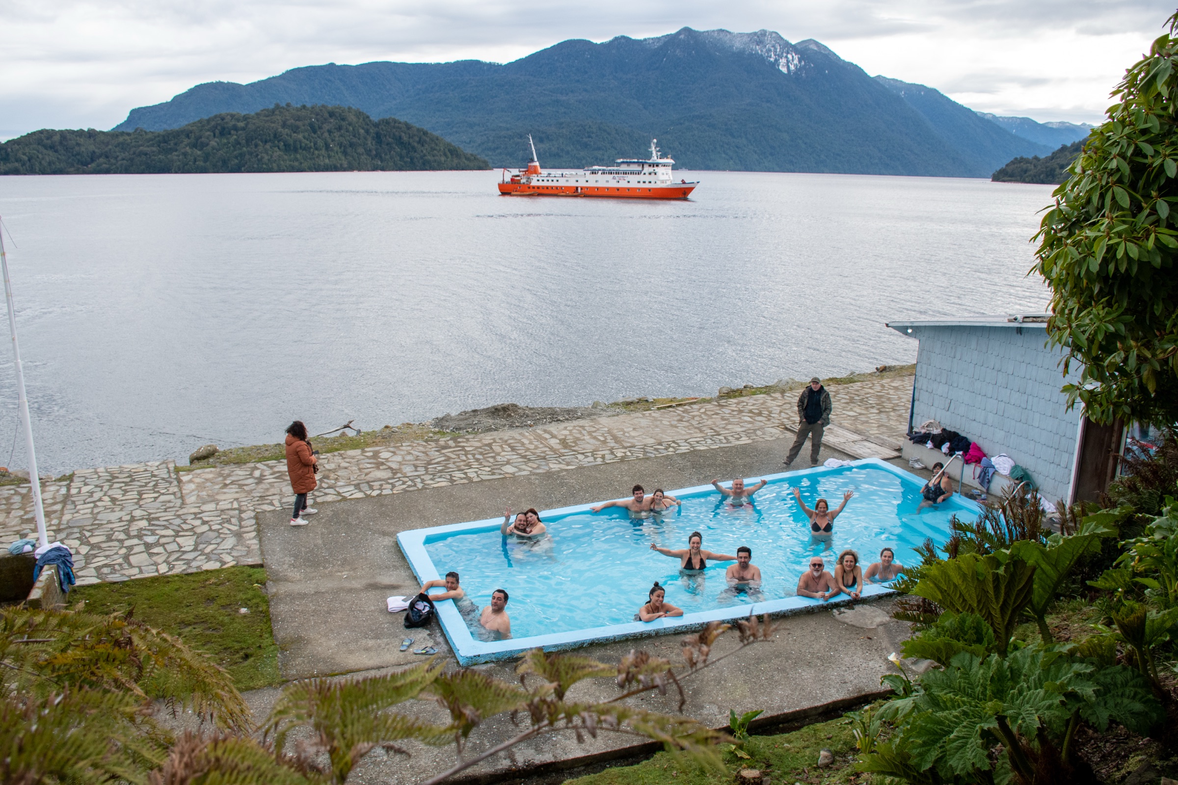 Pasajeros bañándose en las Termas de Llancahué frente al fiordo
